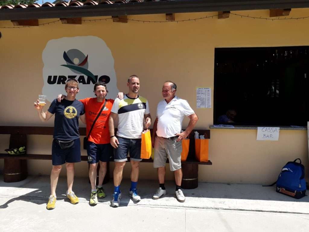 Quattro amici davanti al bar del Circolo, sotto il logo di Urzano